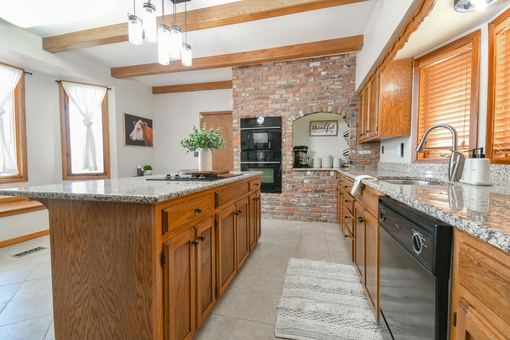 Large kitchen with wood cabinets and oven inset into a brick accent wall